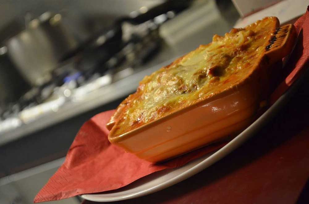 Lasagna al forno in een terracotta schaal